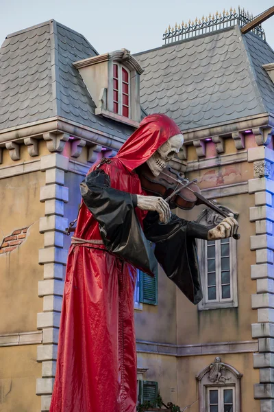 Bad Duerkheim, Germany - September 10 2016. Mysterious red hooded skeleton figure playing violin in front of a mystic castle in the amusement park of folk festival