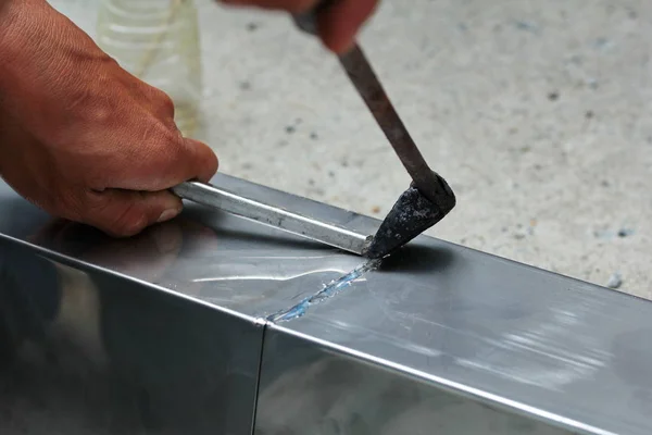 Aluminium gutter welding by using soldering copper with picnic gas:Technician is welding aluminium pipe by using soldering copper.