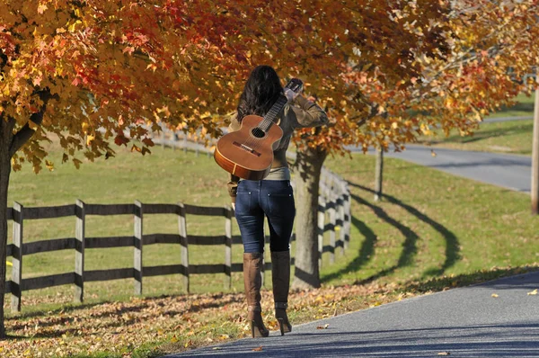 Woman Walking Away with Guitar in the Fall