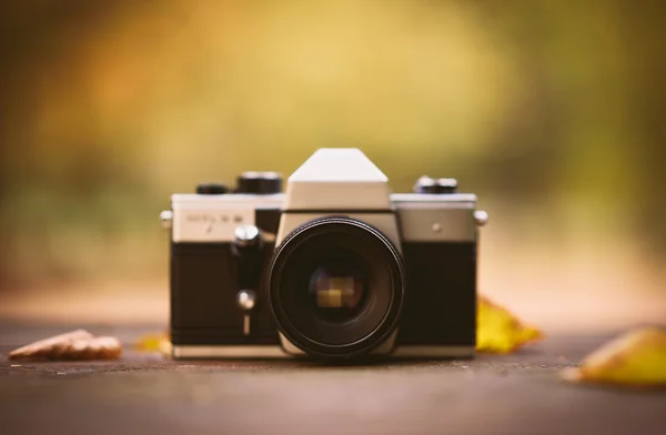Vintage camera on a wooden desk in the park. Product photograph with shallow depth of field