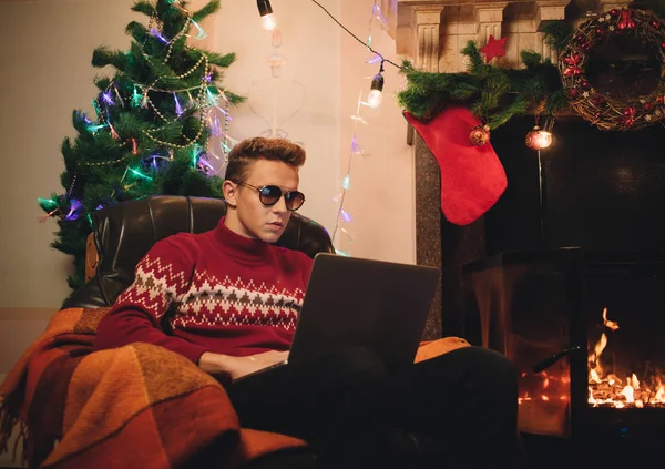 Self-assured male makes a purchase on the Internet via a laptop with sunglasses