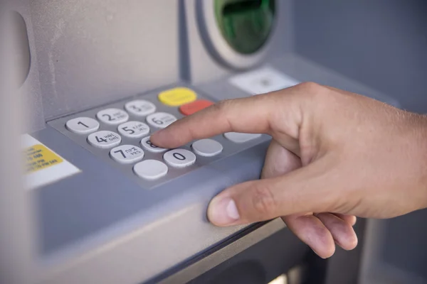 Close-up of hand entering PIN/pass code on ATM/bank machine keyp