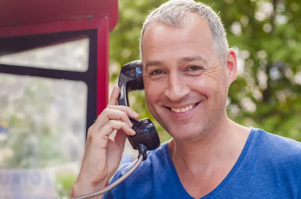 Handsome Man doing a call in a telephone box