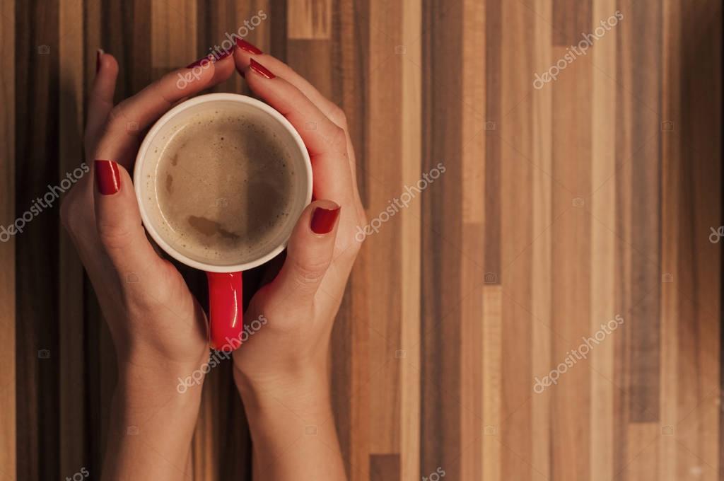 Manos de la mujer sosteniendo la taza con café, vista superior ... Mesa con madera rústica en l