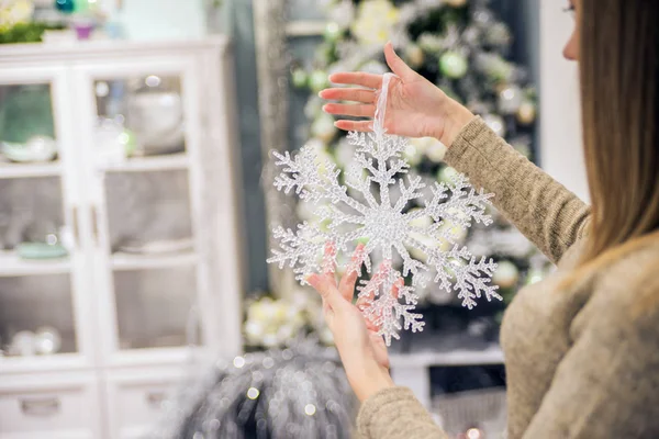 Woman's Hand Holding Snow Flake Decoration. winter, people, happiness concept - woman in hat, muffler and gloves with big snowflake