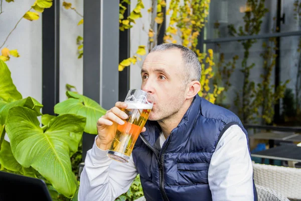 Man drinking beer. Side view of handsome young man drinking beer while sitting at the bar counter. Men drinking beer. Portrait of handsome young men drinking beer and looking away