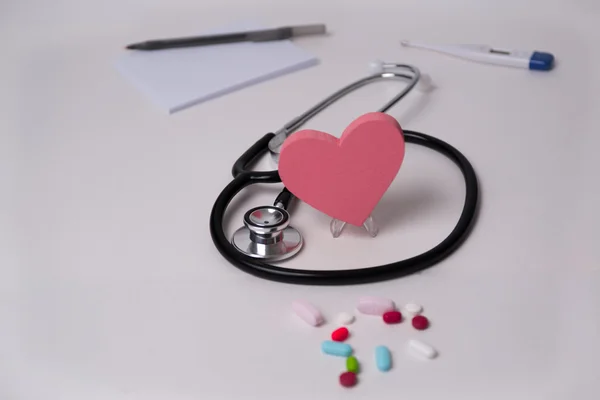 Stethoscope and tablets, heart in the middle, prescription, tablet pen, and thermometer photo for heart disease,