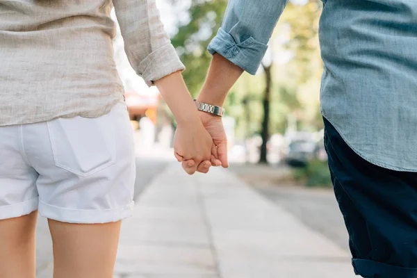 Male female hold hands on walkway in daylight