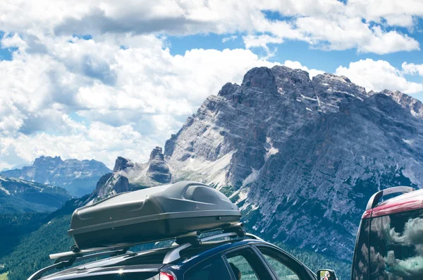 Cars in a parking lot in a middle of mountains. Vehicles on a beautiful sunshine. Transportation background