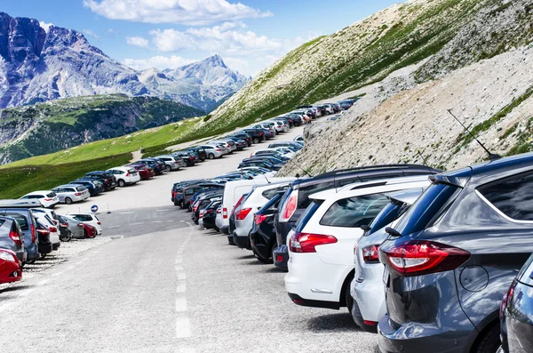 Cars in a parking lot in a middle of mountains. Vehicles on a beautiful sunshine. Transportation background