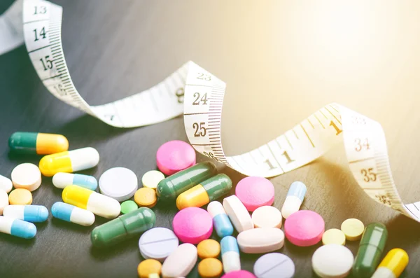 Pharmacy background on a black table with measuring tape. Tablets on a black background. Pills. Medicine and healthy. Close up of capsules. Differend kind of pills