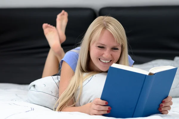 Young woman grinning as she reads a book