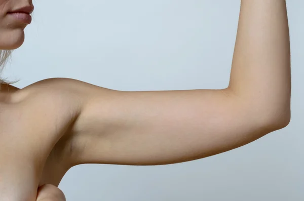Young blond woman showing flabby arm