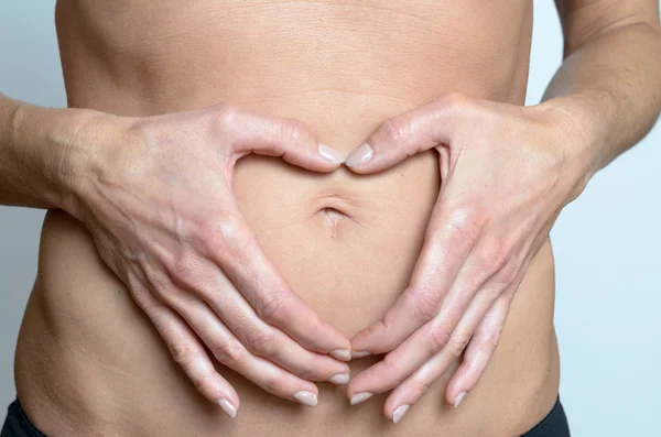 Woman making heart sign on her belly