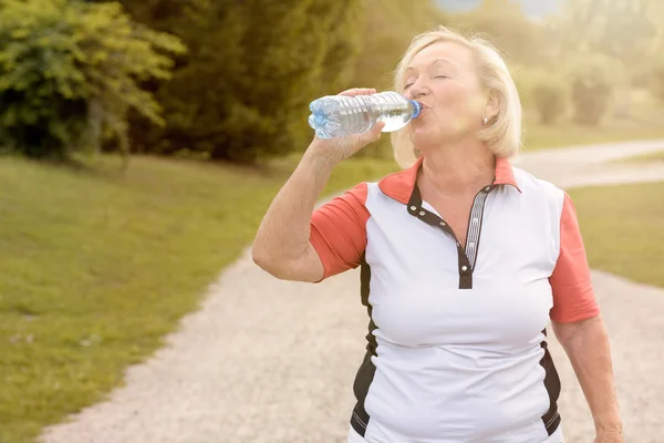 Healthy senior woman drinking bottled water