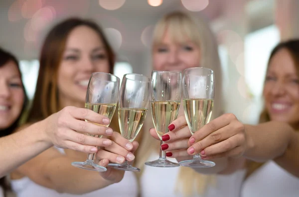Four young women toasting with champagne
