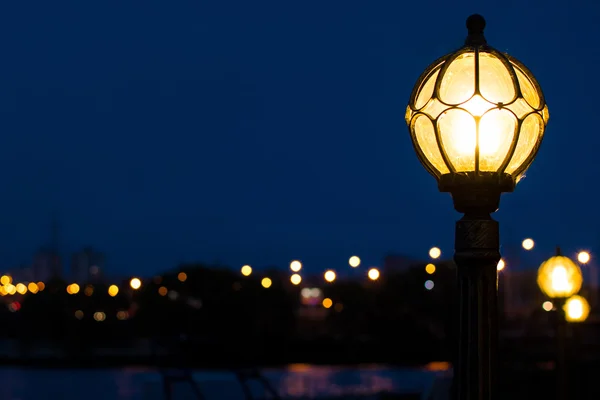 Night streetlight near city river with a bokeh of urban lights