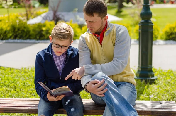 Young man is helping teenager to read a book