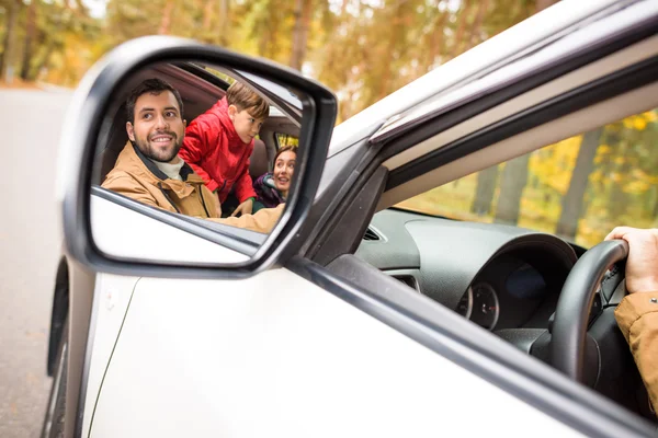 Happy family reflected in car mirror