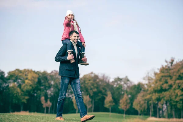 Smiling father carrying daughter on shoulders