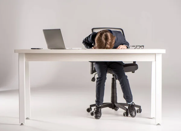 Schoolchild in business suit sleeping on desk