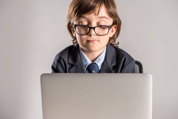 Schoolchild in business suit using laptop