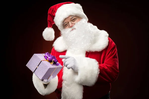 Santa Claus pointing on gift box