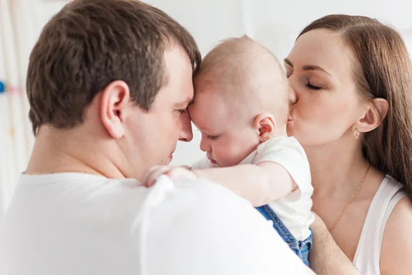 Father and mother kissing baby son