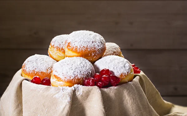 Fresh donuts (sufgania) with jam and dried cherries on a cotton material. Hanukkah holiday celebration and traditional jewish sweet