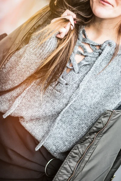 Young fashionable woman smiling while wearing a perfect autumn outfit - bomber jacket and an oversized grey lace up sweater.