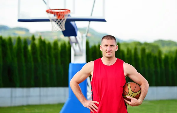 Basketball player with ball at the outdoors basket court