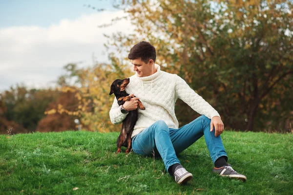 Dog and his owner, cute dog and young man having fun in a park, concepts of pets, animals, togetherness, friendship