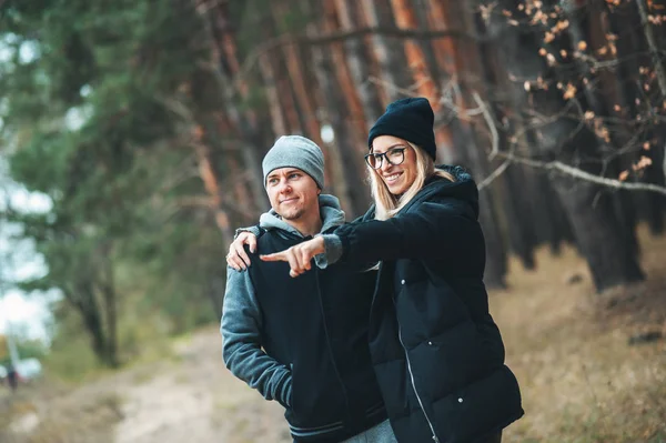Portrait of couple young man and woman in forest. Couple hugging and smiling. Young girl point on something to her boyfriend.