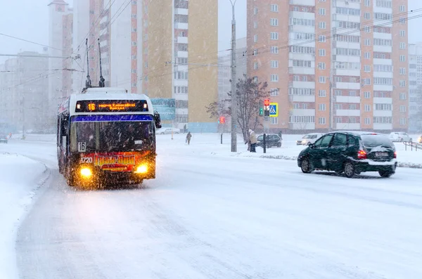 Троллейбус на городской улице во время сильного снегопада — стоковое изображение Троллейбус на городской улице во время сильного снегопада — стоковое фото