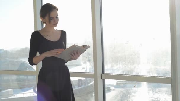 Женщина с книгой за окном — стоковое видео