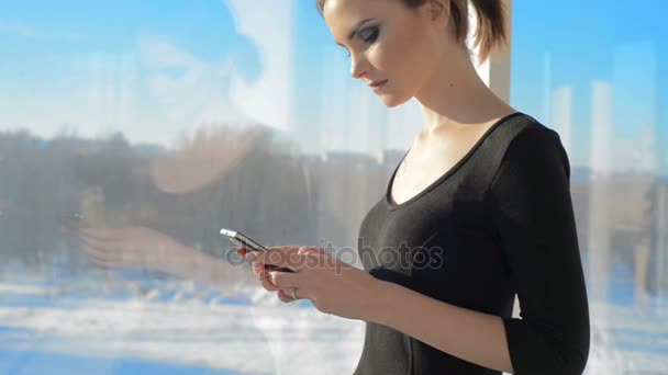 Женщина с телефоном за окном — стоковое видео