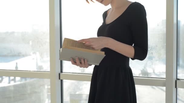 Mujer con libro por ventana — Vídeo de stock