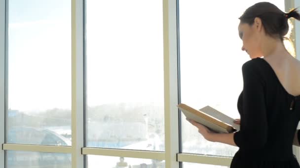 Mujer con libro por ventana — Vídeo de stock