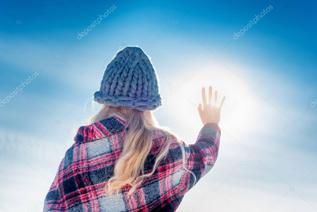 woman reaches hand to the sun