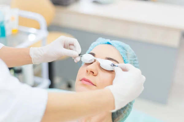 Esteticista pone gafas protectoras en el paciente — Foto de Stock
