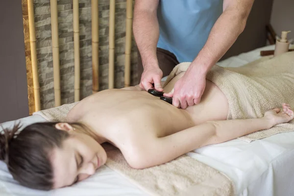 Giovane bella donna in spa ottenere massaggio con pietre calde — Foto Stock