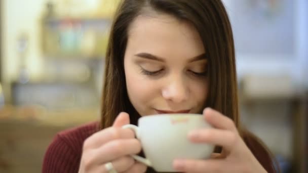 Mujer joven bebe capuchino café — Vídeo de stock