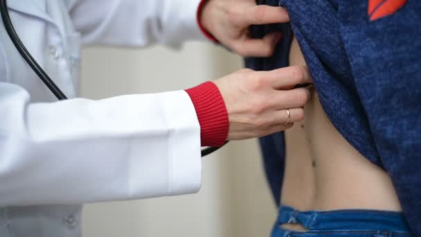 Doktor sprawdzanie lub badania płuc ausculting na tylnej części młodych pacjentki z stetoskop — Wideo stockowe
