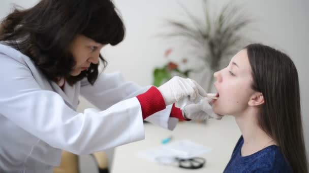 Médico revisando o examinando la prueba de hisopo de garganta paciente femenina joven — Vídeo de stock