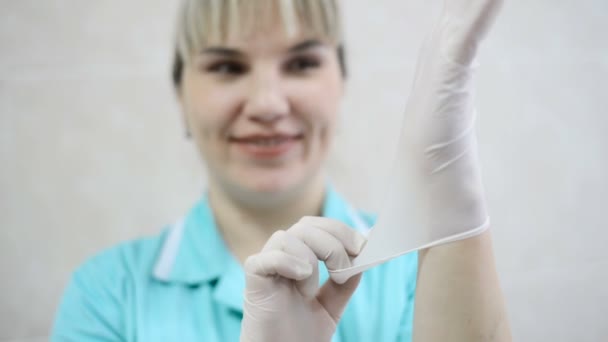 Heureuse drôle femme infirmière ou médecin en robe médicale sourit et étire des gants en latex stériles avec les mains — Video