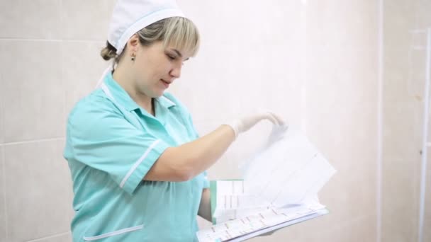 Arzt Krankenschwester Krankenhaus blättert Magazin Ergebnisse Patienten. Arzt füllt das Registrierungsformular des Patienten aus und verschreibt die Behandlung — Stockvideo