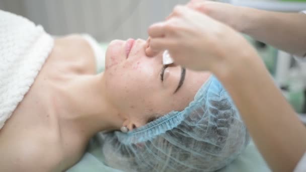 Schoonheidsspecialist crème voor de vrouw van het gezicht en massages met cosmetische behandeling in spa. Professionele schoonheidsspecialist masker toe te passen op de vrouw op de salon van de schoonheid. Huid gezicht procedures cosmetologie schoonmaken. — Stockvideo