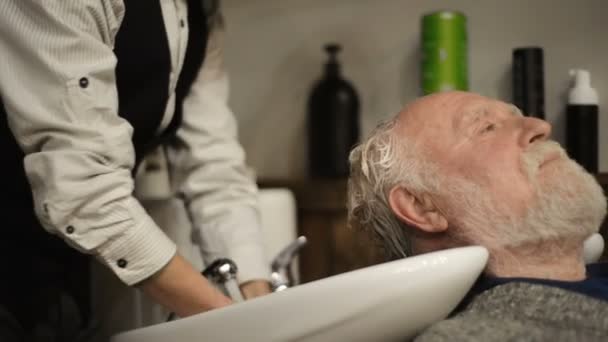 Retraité actif vieux barbu homme âgé âgé avec des cheveux gris dans coiffeur coiffeur coiffure obtenir lavage tête de cheveux — Video