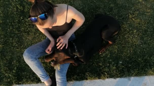 Jente eller kvinne går tur og leker med Doberman Pinscher-hund i parken nær innsjøen i forbindelse med solnedgang – stockvideo