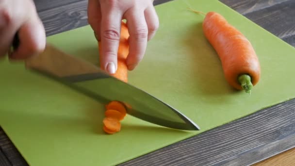 Mãos de mulher cortando cenoura ou legumes. Cozinhar comida vegan . — Vídeo de Stock